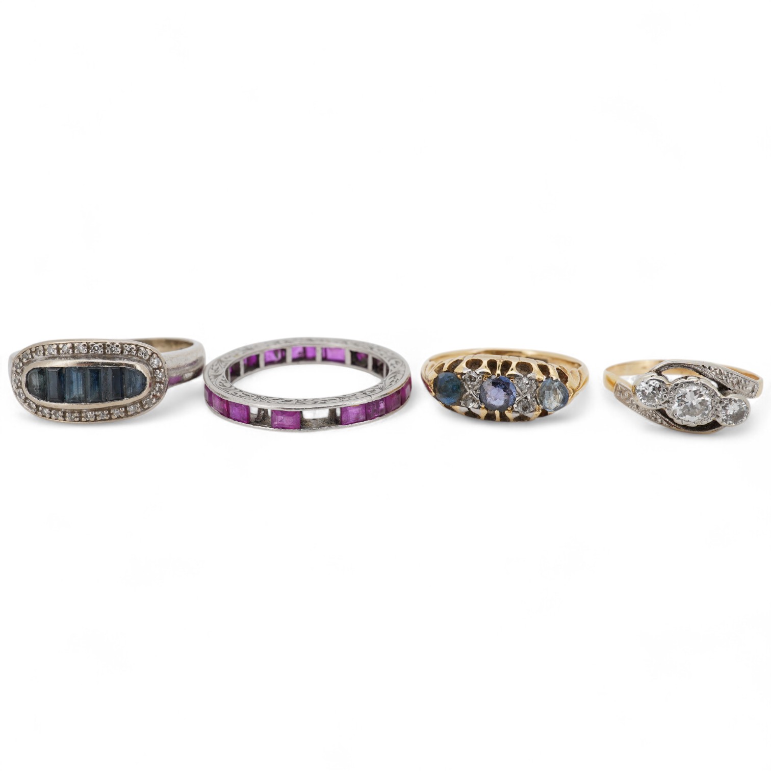 A yellow metal and illusion set three stone diamond crossover ring, size I, an 18ct, sapphire and diamond chip set ring, a modern 18ct gold and six stone sapphire set ring, with diamond chip border and an engraved white